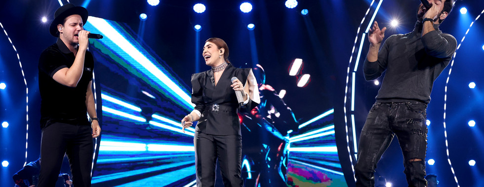 Artistas convidados participam da gravação do projeto Naiara15 ao lado de Naiara Azevedo no palco, durante apresentação ao vivo com iluminação de show e atmosfera festiva celebrando os 15 anos de carreira da cantora.