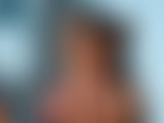 na Castela sorrindo com chapéu e microfone em show na praia.