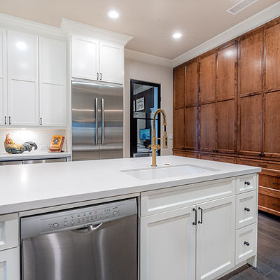 Kitchen island cabinets, white countertop, and a gold faucet.
