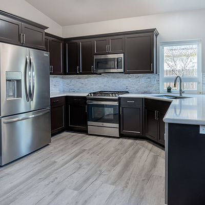 Kitchen renovated with black cabinetry and light wood look flooring.