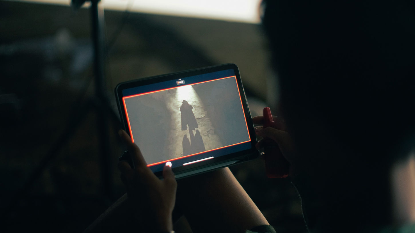 Hands holding a tablet that shows the camera feed of a night scene