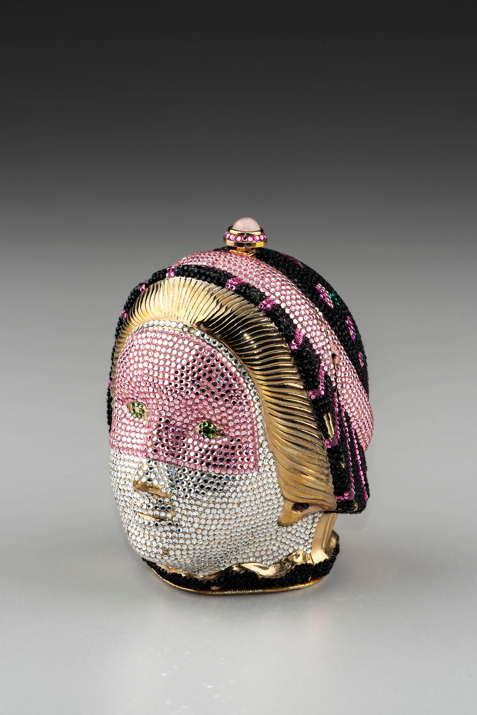 Judith Leiber (American, 1921–2018).Masquerade Head Minaudiere,1989,gold-plated brass, leather,Swarovskicrystals, semipreciouscabochon stone. Gift of the family of Vicki and Jim Mills. 2025.34.14a-d