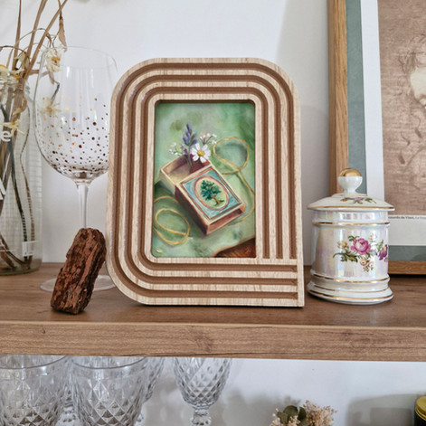 Mise en scène d'une peinture miniature encadrée, posée sur une étagère rétro, entourée d'objets du quotidien