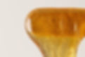 Close-up of golden honey dripping with a white background beauty services