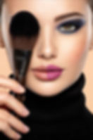 Woman's face with split lip in two colors, smoky eye; brush partly obscures, adding intrigue
