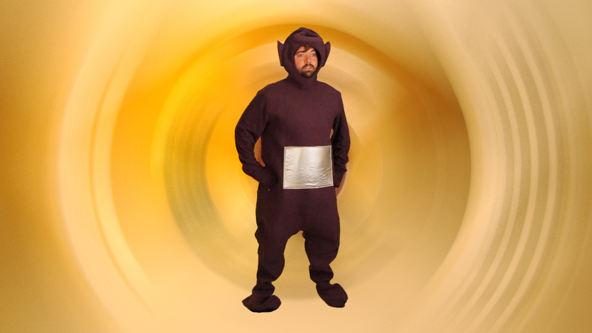 man in awkwardly fitting Tinky Winky costume with swirled background