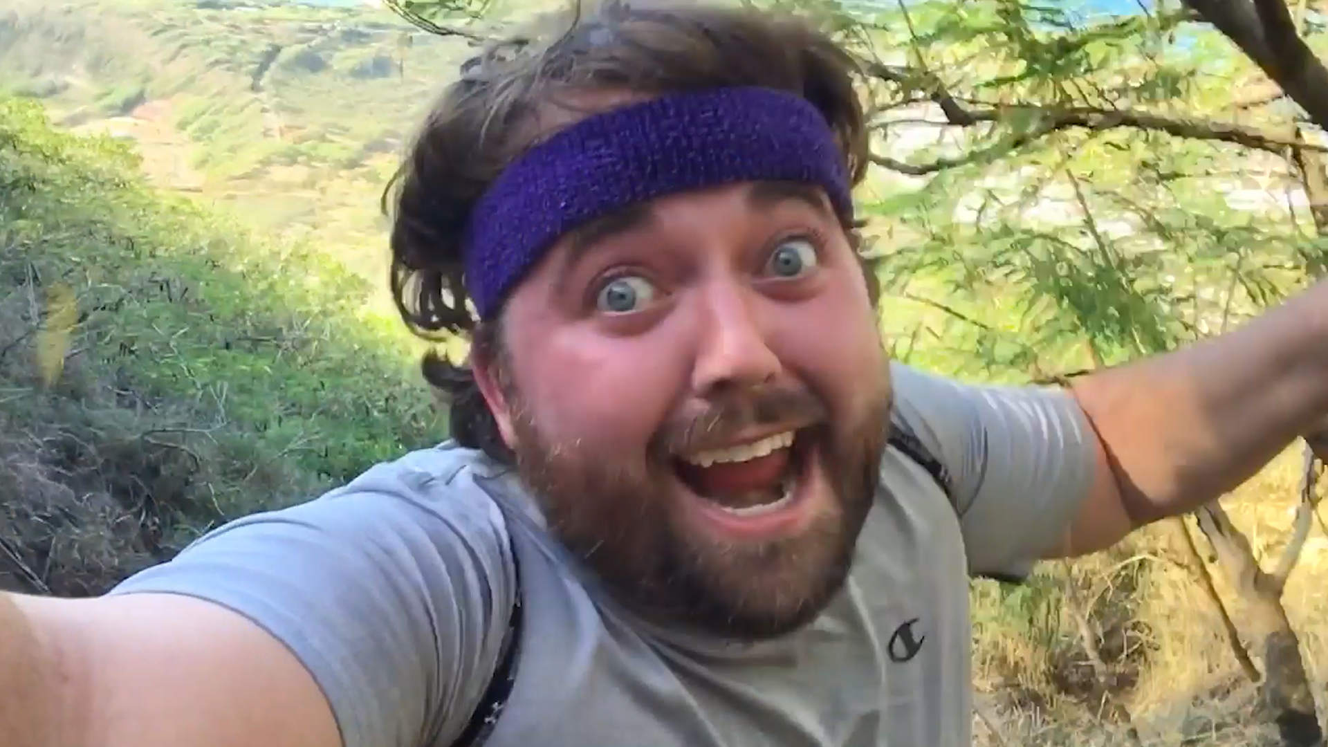 hiker with headband and big smile in front of grassy area