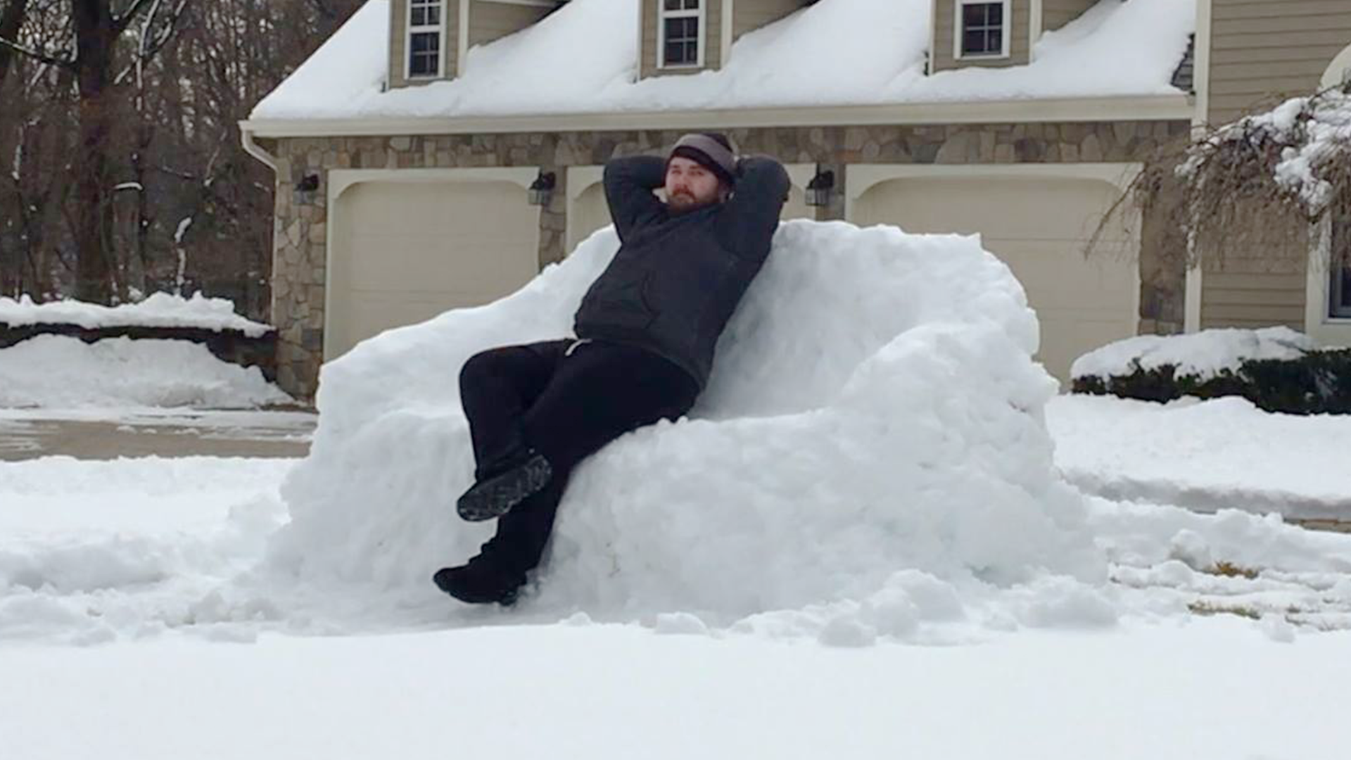 man kicking back on couch made out of snow on snowy lawn
