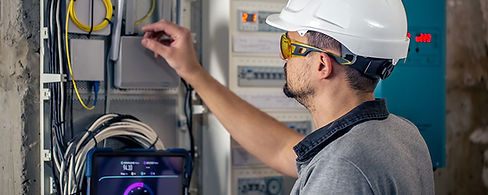 man-electrical-technician-working-switchboard-with-fuses-uses-tablet.jpg