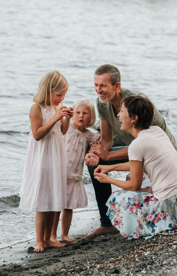 Familie fotografert på stranden. De studerer et skjell