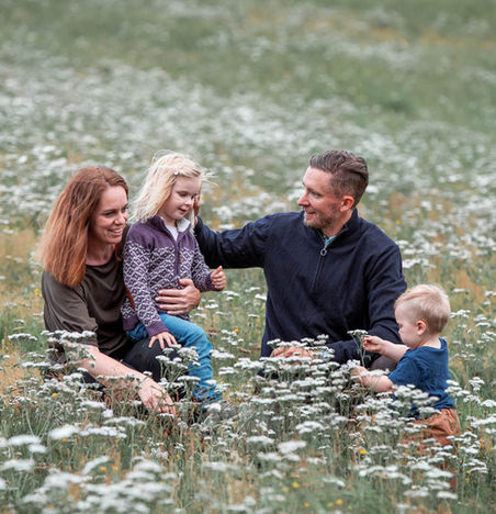familie med små barn fotografert i blomstereng med hvite blomster