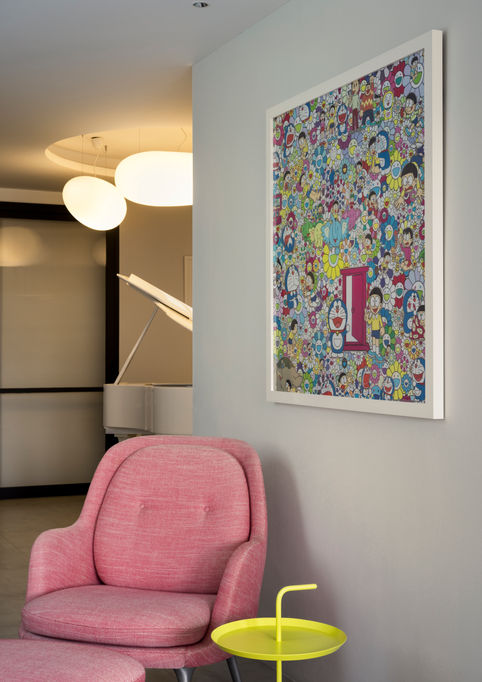 Cozy seating corner featuring a plush pink armchair, a small yellow side table, and a large piece of colorful abstract artwork mounted on the wall.