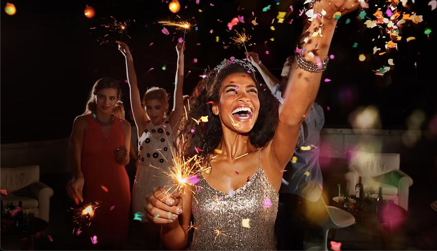 A woman with a sparkler celebrating the new year at a party.