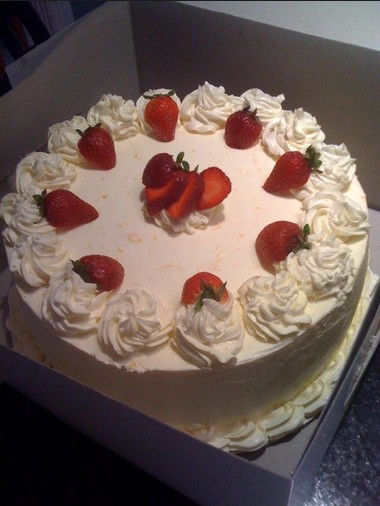 White Cake with buttercream frosting and sliced strawberries and cream filling.