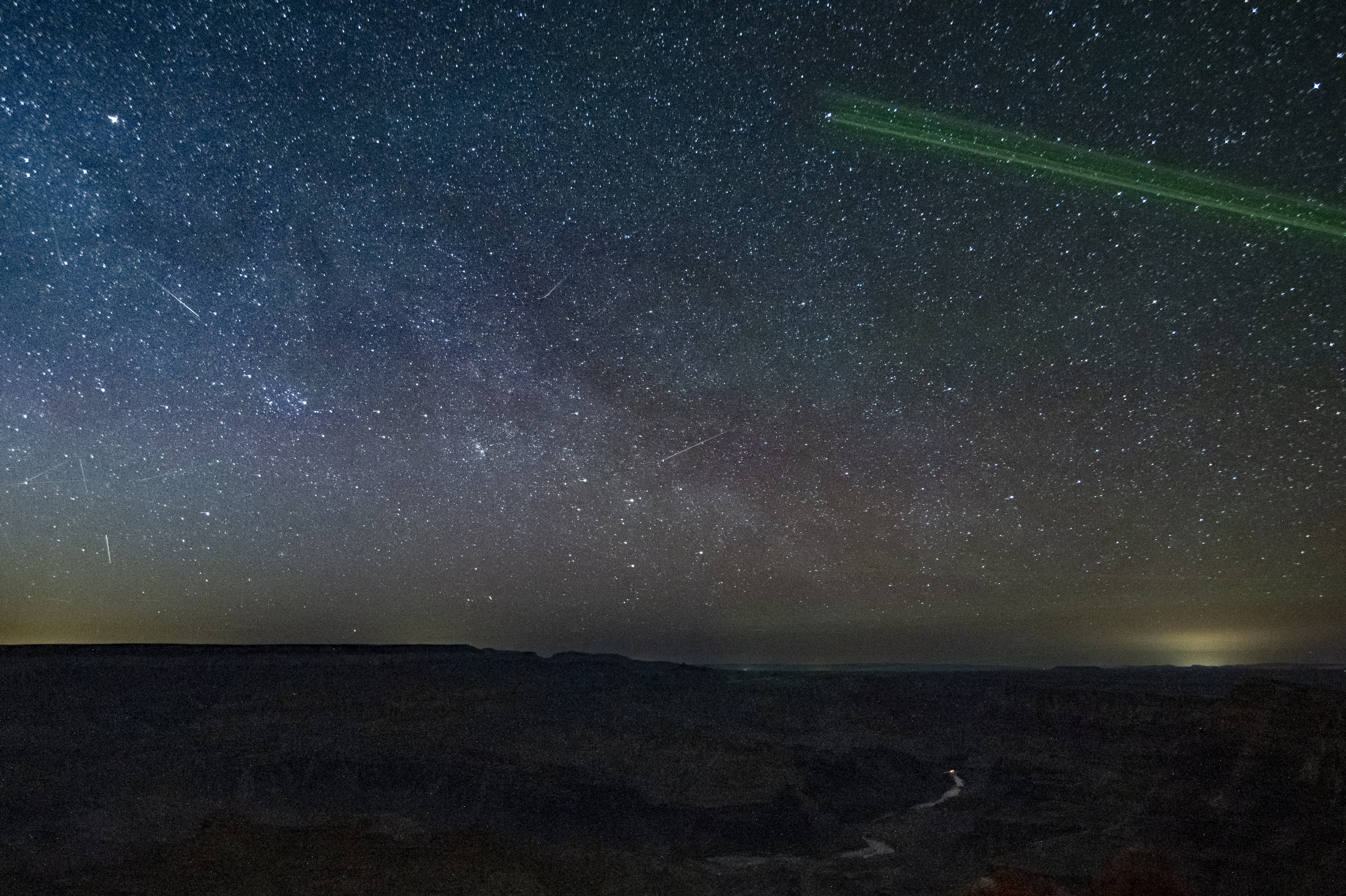 A breathtaking view of the Milky Way galaxy stretching across the dark sky above the Grand Canyon rim.