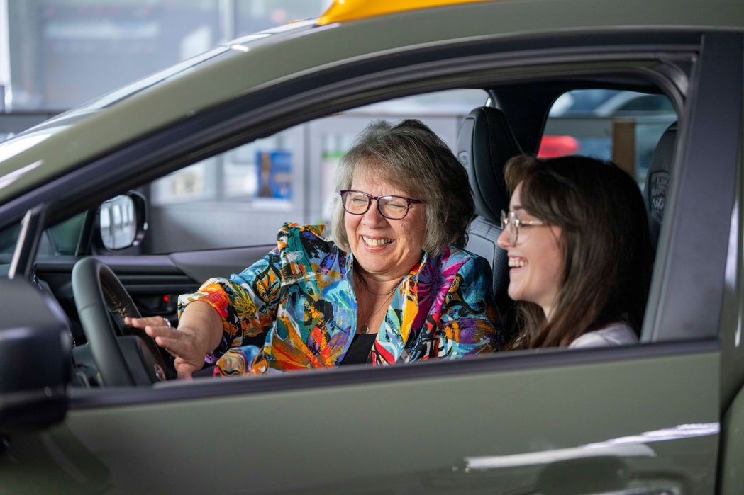 A dealership employee sitting in a vehicle with a customer during a video shoot.