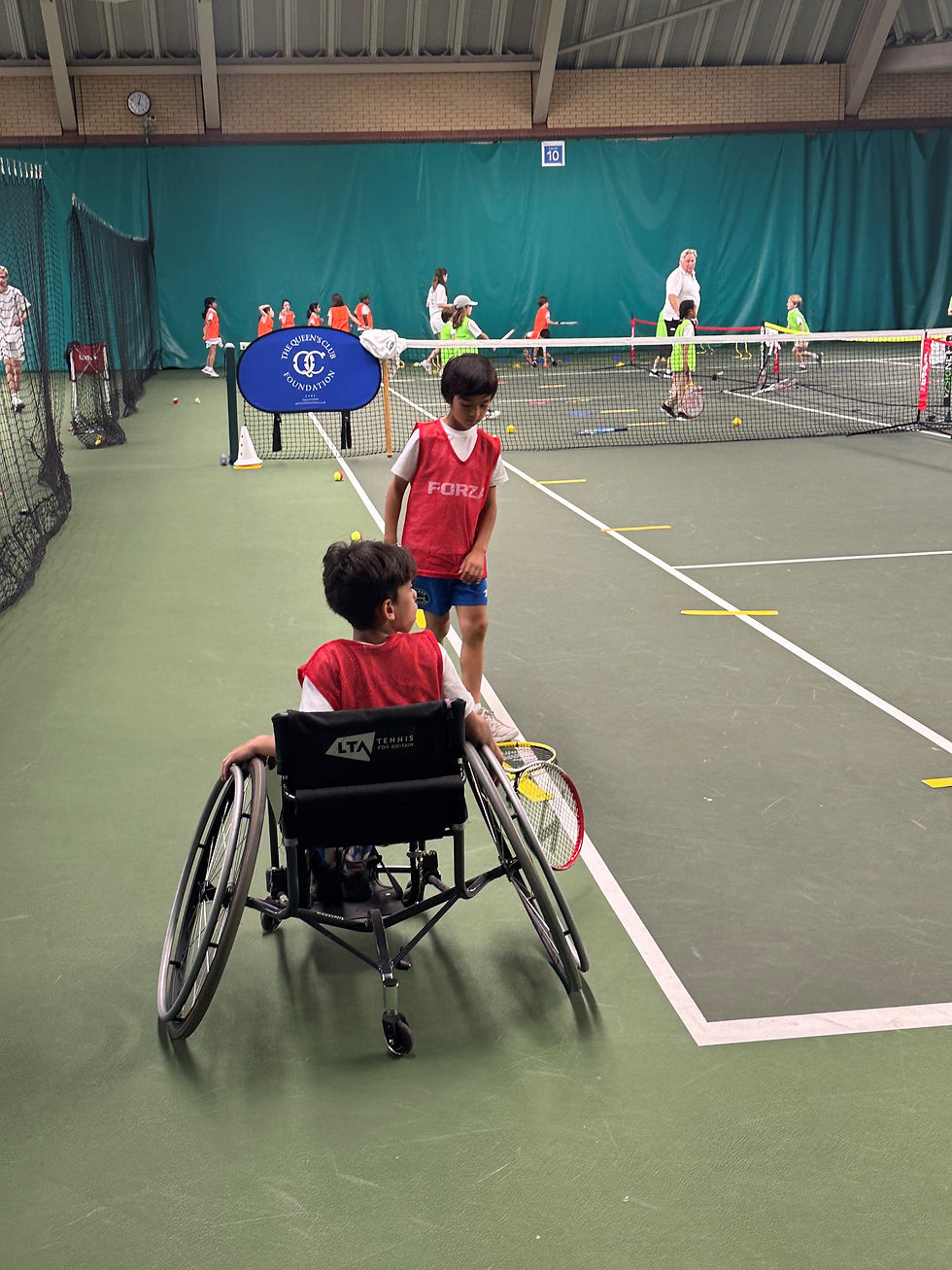 A boy in a wheelchair playing tennis with other children