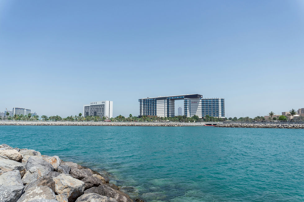 Buildings stand next to the bright blue sea.