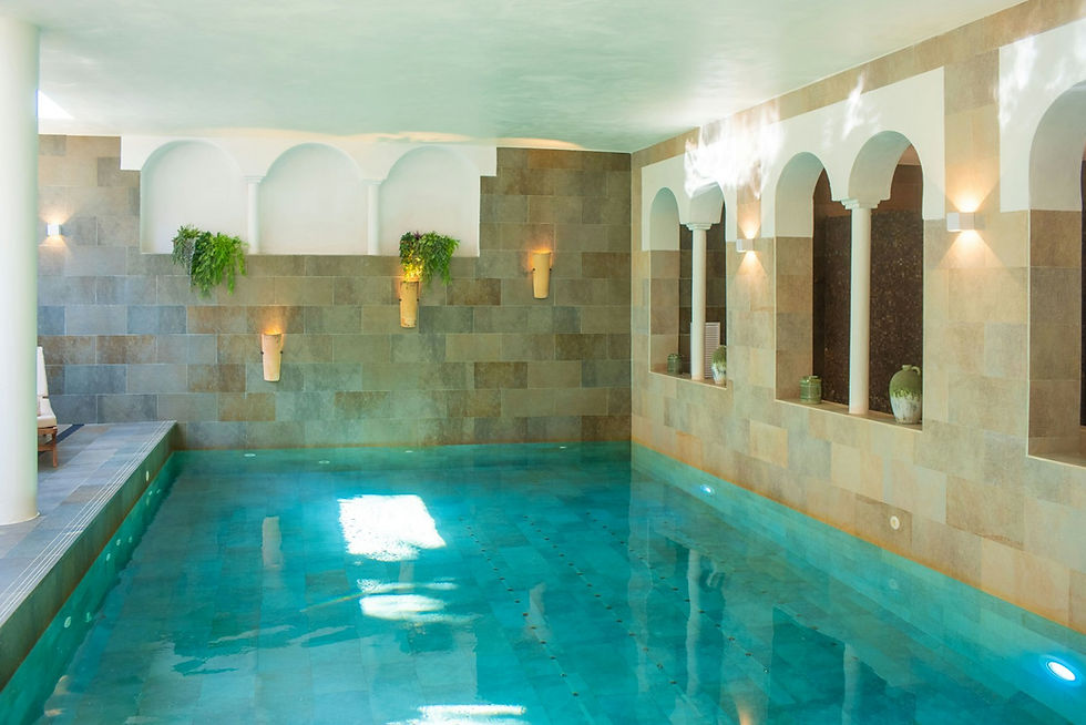 An indoor swimming pool surrounded by stone walls and natural light