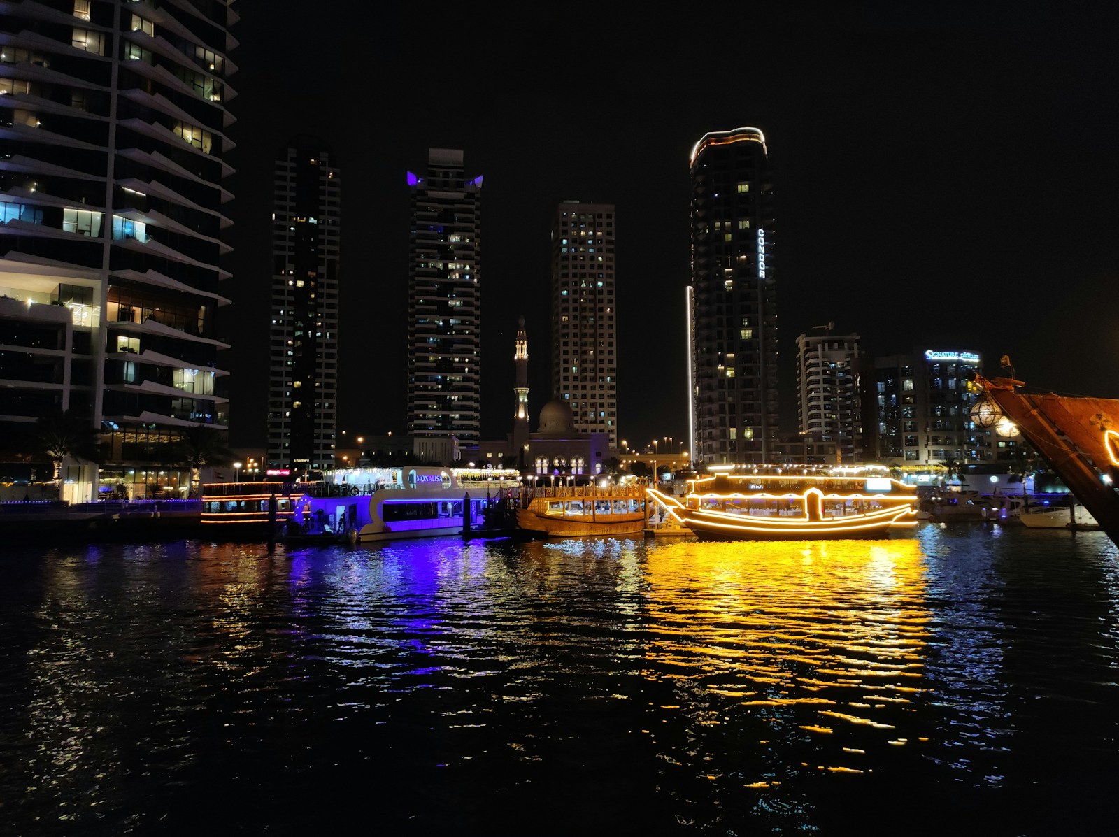 Dubai Marina at night with illuminated dhow boat and lit towers reflected in the canal