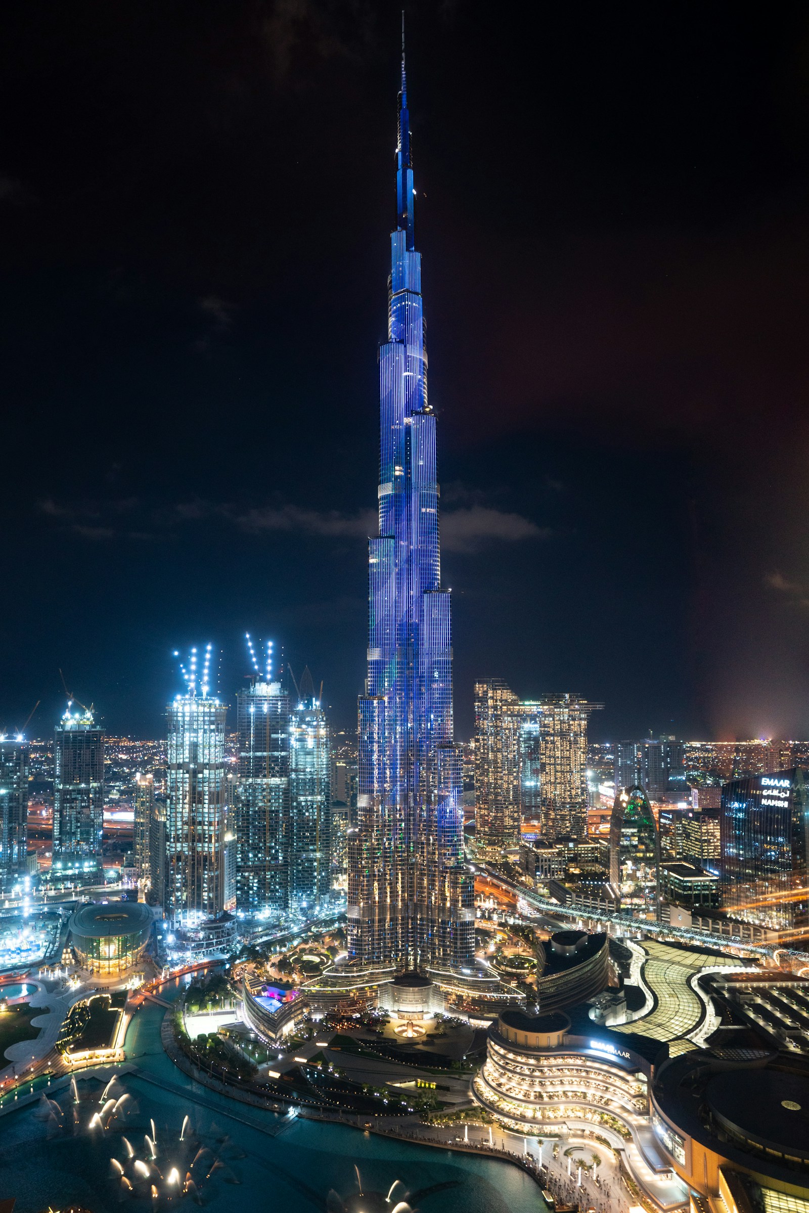 Burj Khalifa fully illuminated in blue at night — downtown Dubai skyline with fountains below