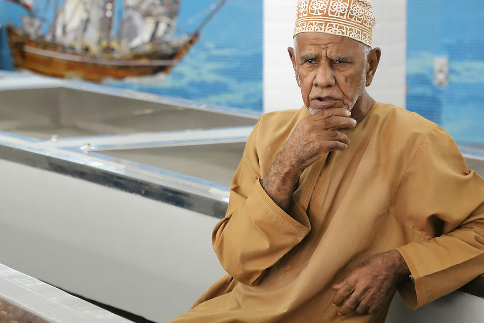man in yellow thobe sitting on white boat during daytime