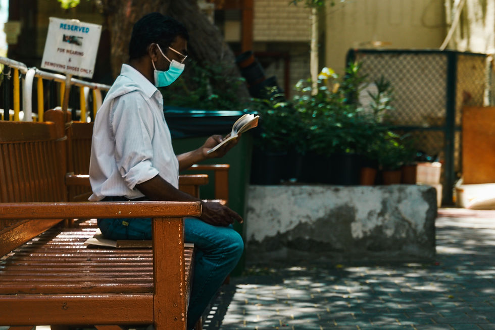 Man sitting on bench reading a book in Deira, Dubai city centre