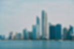 Abu Dhabi city skyline viewed from the water, with glass towers in cool blue tones
