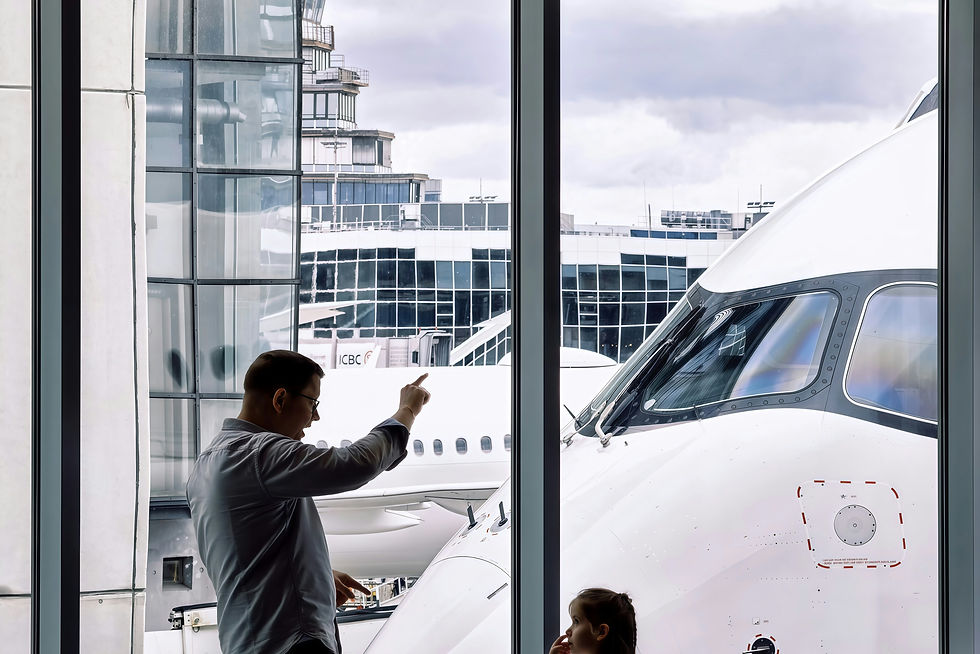 Father and daughter look at airplane at airport gate.