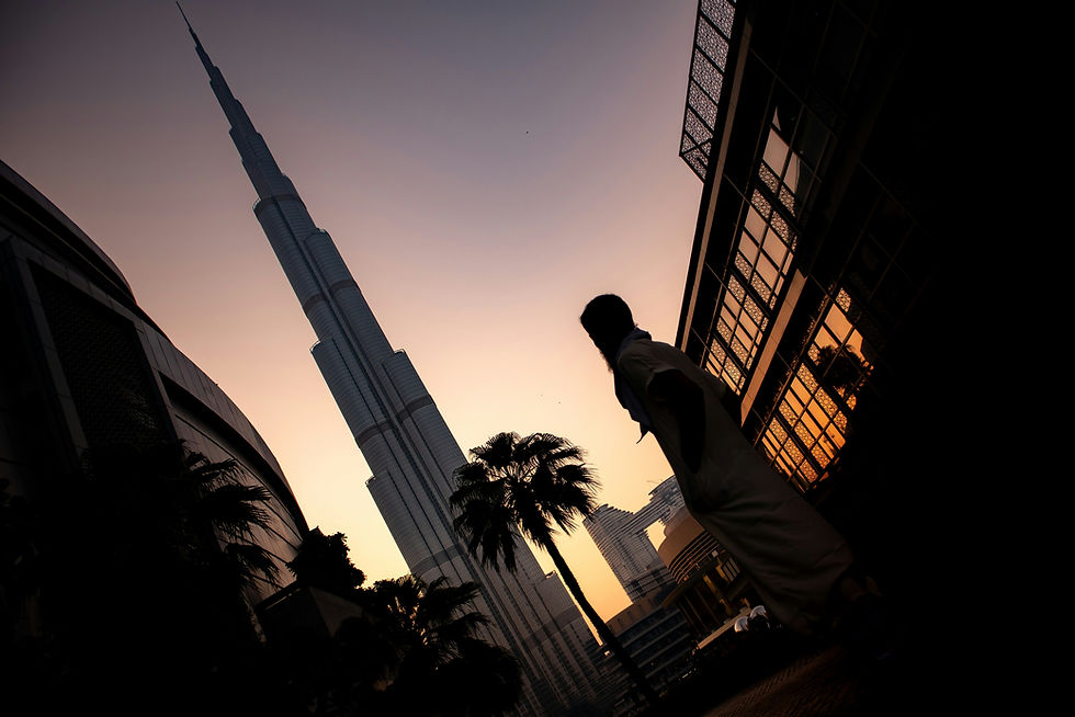 A low angle shot of a person standing near Burj Khalifa hotel during sunset in Dubai, UAE