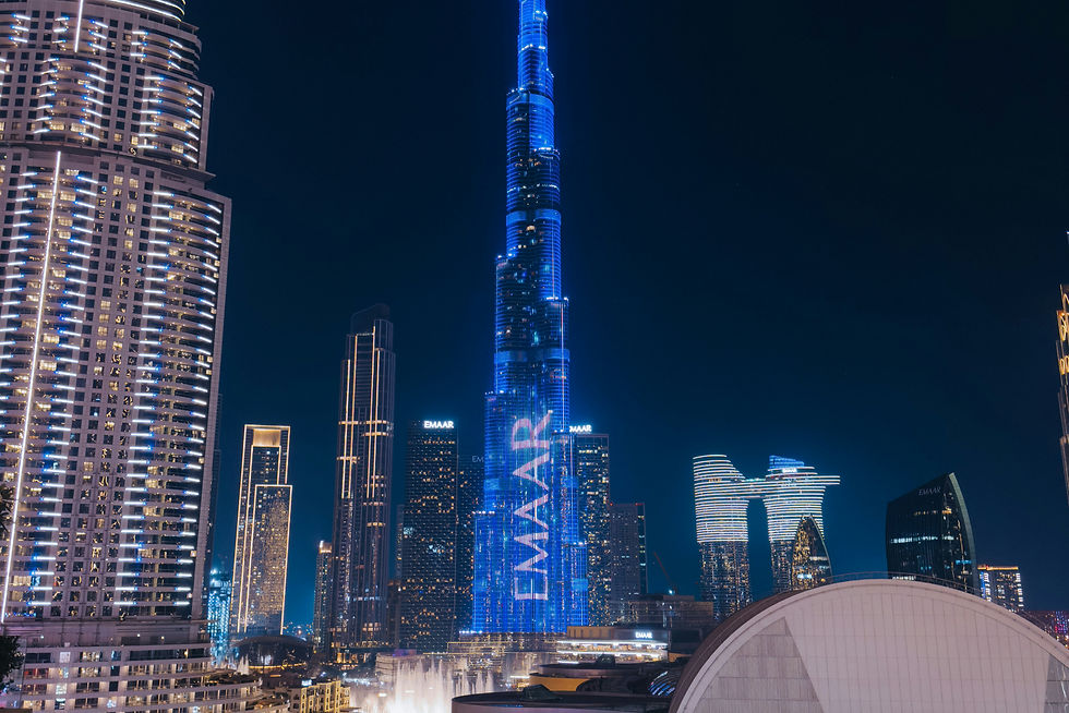 A rooftop infinity pool glows turquoise at night as the Burj Khalifa, lit blue, towers over the Downtown skyline.