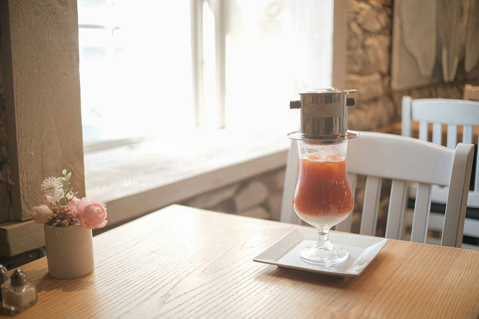 Coffee dripper over a colorful drink on a cafe table.