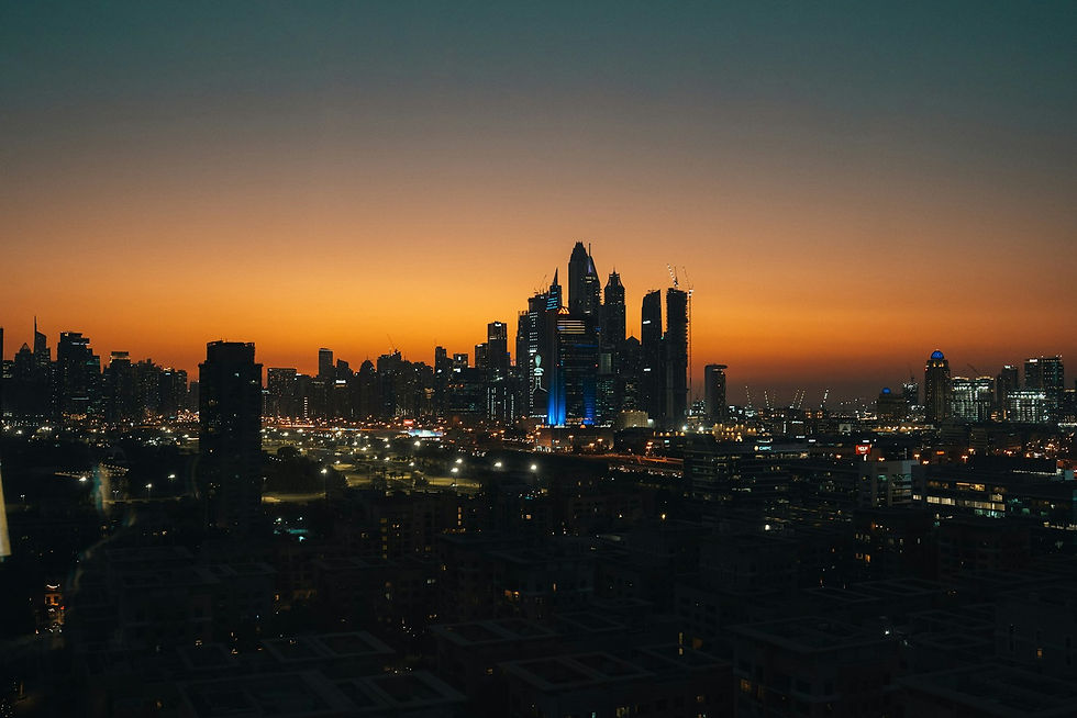 Dubai city skyline at dusk with financial district towers illuminated against orange sky
