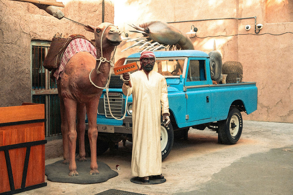 Life-size mannequin and camel sculpture standing before a vintage blue Land Rover in Dubai.