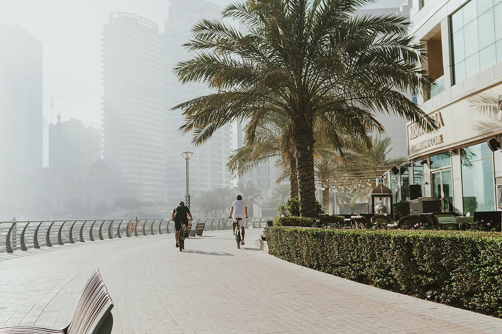 Cyclists and a pedestrian on a shaded waterfront promenade in Dubai Marina