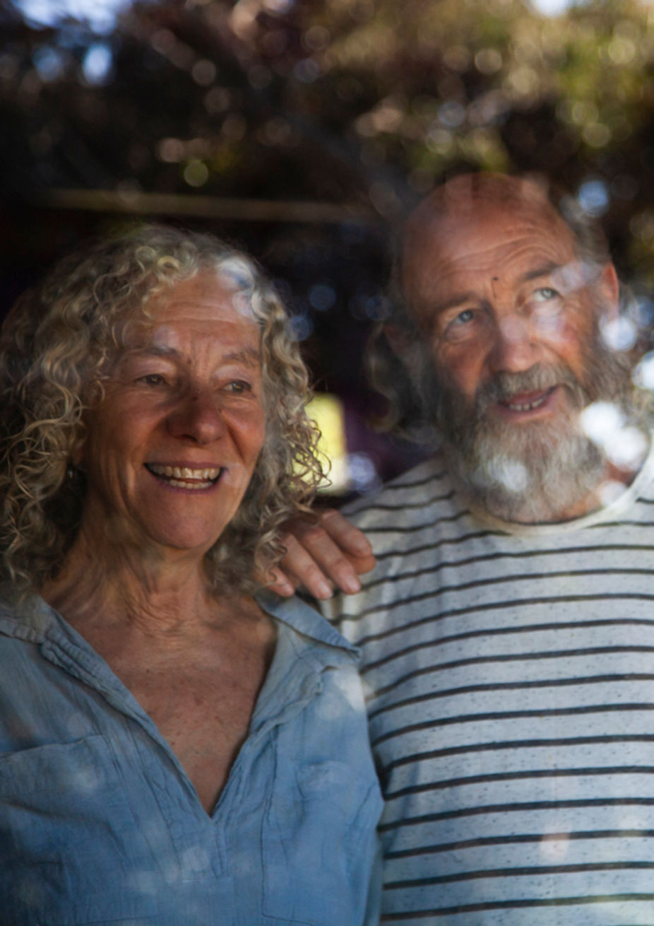 casal de escritores homem e mulher atrás de uma janela de vidro com reflexo de arvore