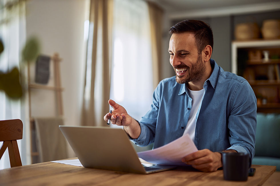 A happy adult hiring manager laughing with a candidate in an online interview while holding his resume papers.