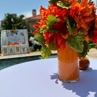 Orange flowers in vase on table by poolside.