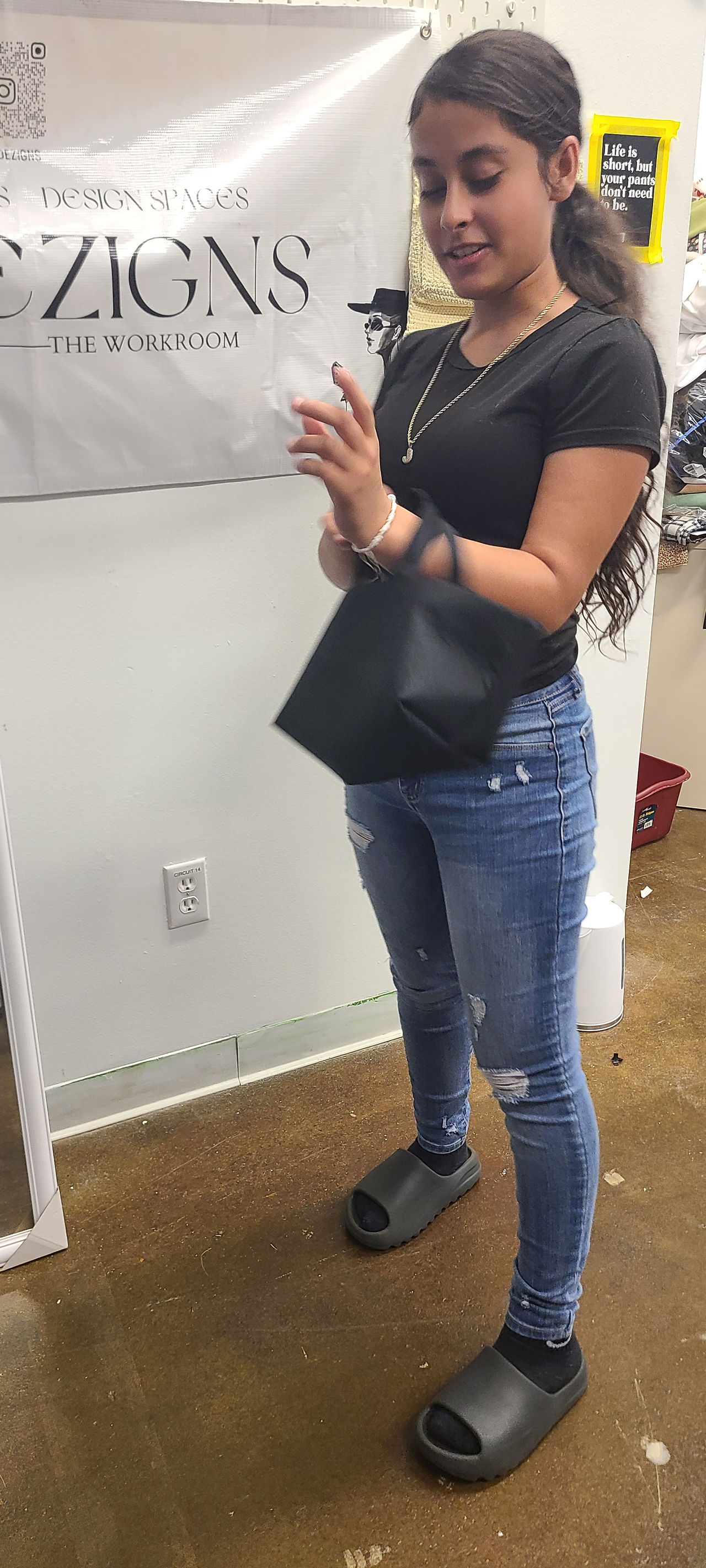 A student holding a black bag she made 