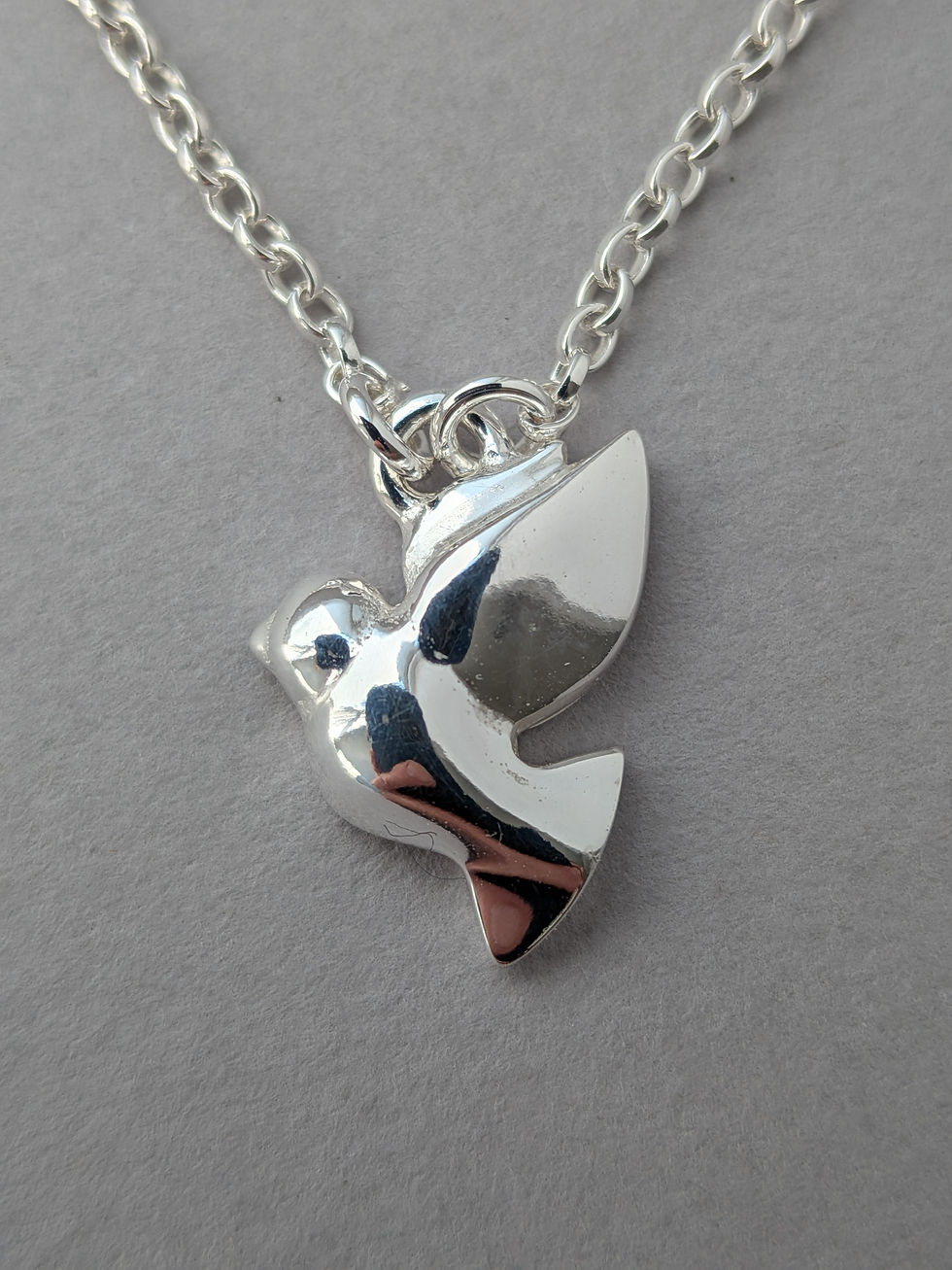Front view on Tiny Dove pendant suspended on chain.