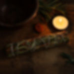 Wild lavender smudge stick on wooden altar with candle, rune stone, and rosemary.