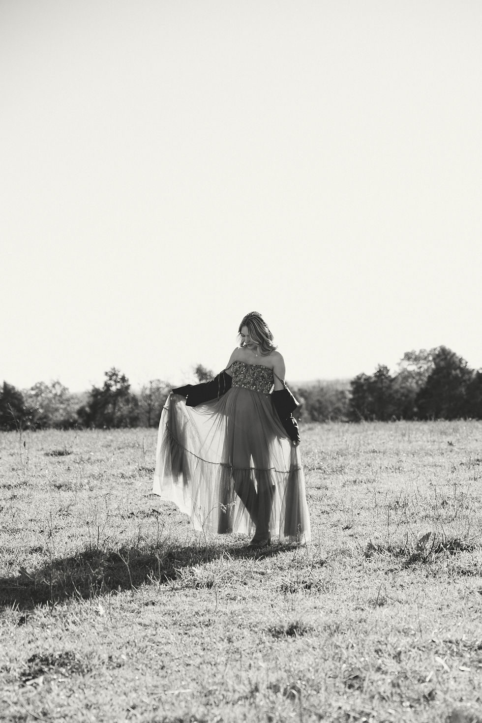 Black and white photo of a mother-to-be cradling her belly, a quiet and emotional moment during her maternity session.