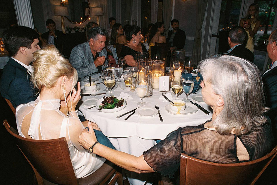 A formal rehearsal dinner for a Charleston wedding at Hall's Chophouse. Photographed on film for an editorial style, the bride wears a slim cut dress with, shear, sleeved top and gold jewelry. 
