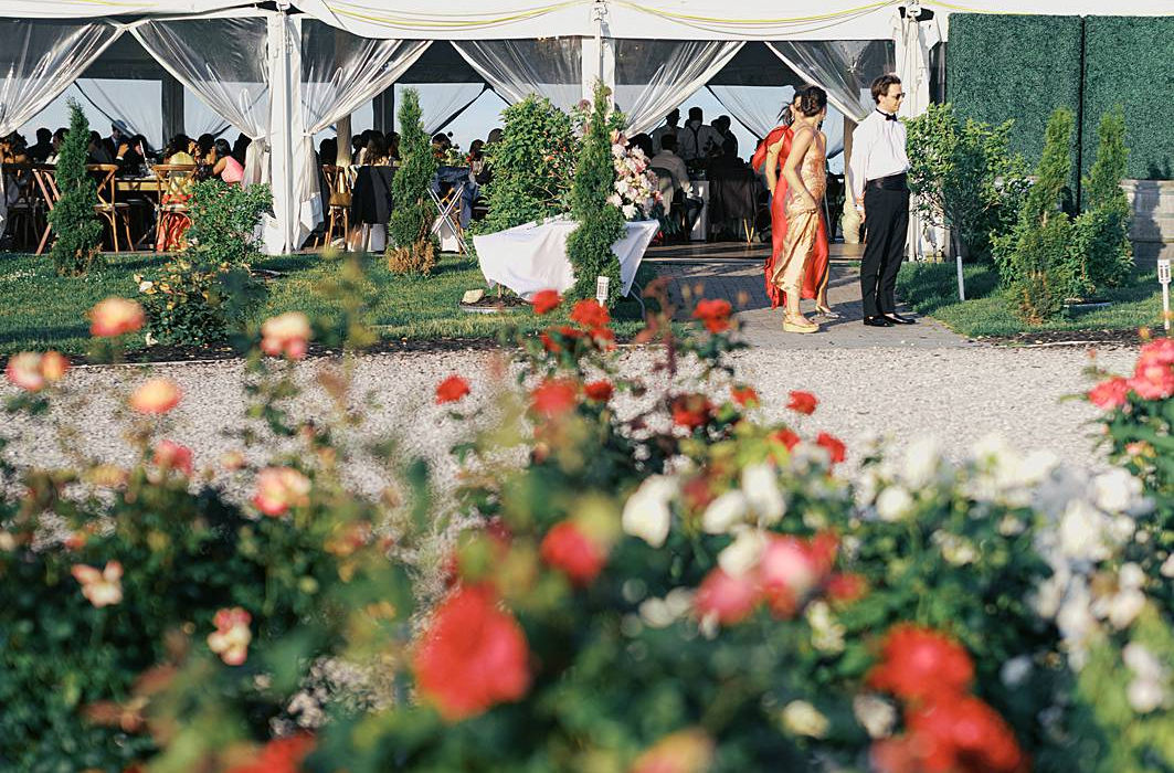 A reception tent from a Traverse City, MI Indian wedding, photographed through the flowers on 35mm film by documentary wedding photographer, Smith Brian.