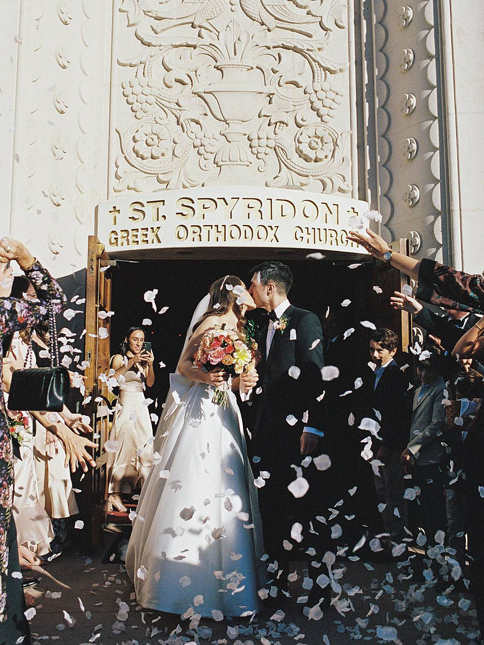 35mm film photograph of a bride and groom on their San Diego wedding day, exiting a church ceremony with guests showering them with rose petals.