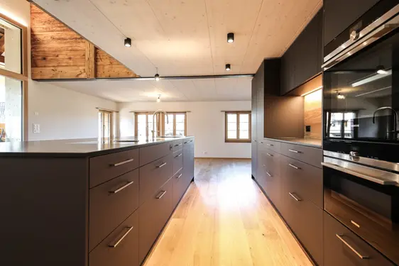 Dunkelbraune Küche mit Kochinsel und Rückwand in Eiche massiv sowie einer Natursteinabdeckung, Madiswil