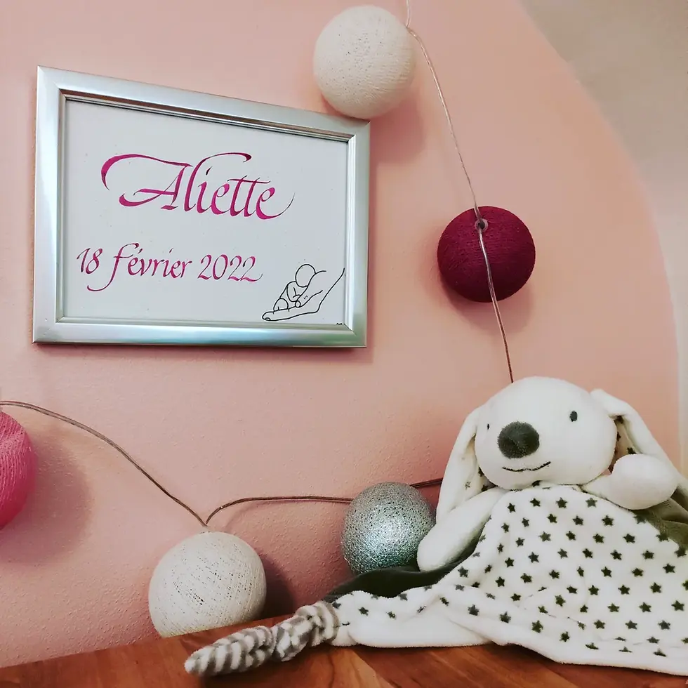 Miniature : Cadre d'une calligraphie avec le prénom et la date de naissance, illustrée par un dessin d'un bébé au creux d'une main, à l'encre rose, pour une déco de chambre d'enfant 100% originale!