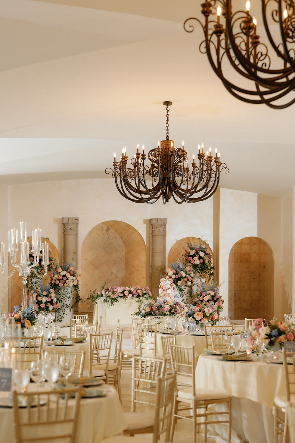 Elegant wedding reception venue with chandeliers, floral installations, and gold chairs, showcasing luxury wedding design and seamless guest experience