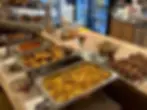 Buffet mit verschiedenen warmen Speisen in Behältern.