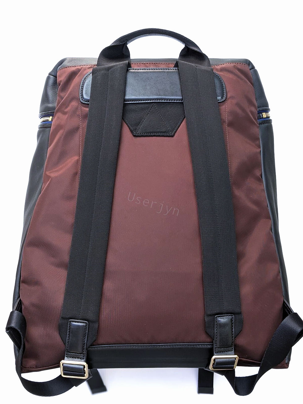 Thumbnail: Brown backpack straps against a black and maroon background Paul Smith design.